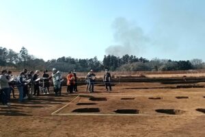 掘立柱建物跡の説明を聞く参加者